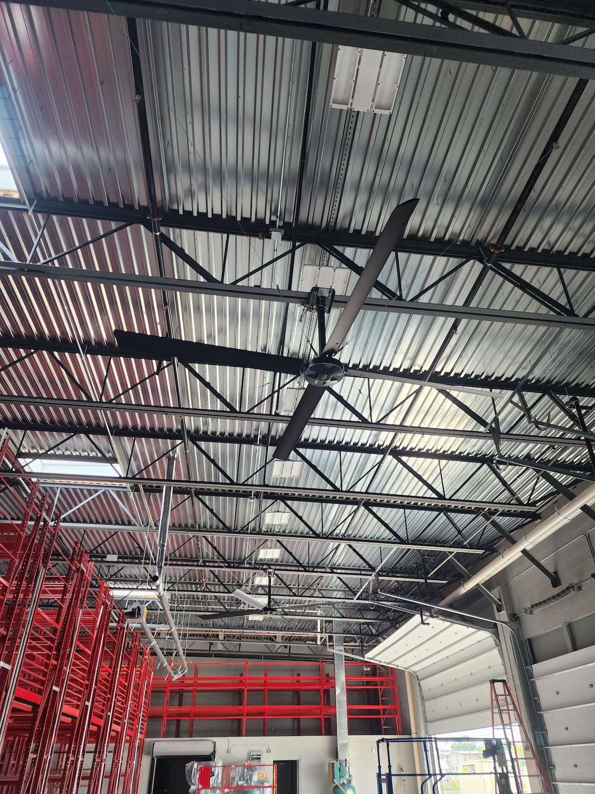 Large ceiling fan in warehouse with red racking